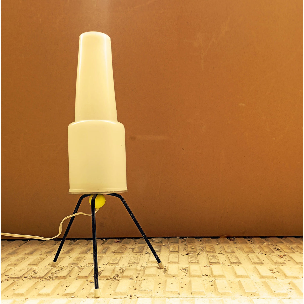 Opal plastic table lamp illuminated against a warm-toned wall
