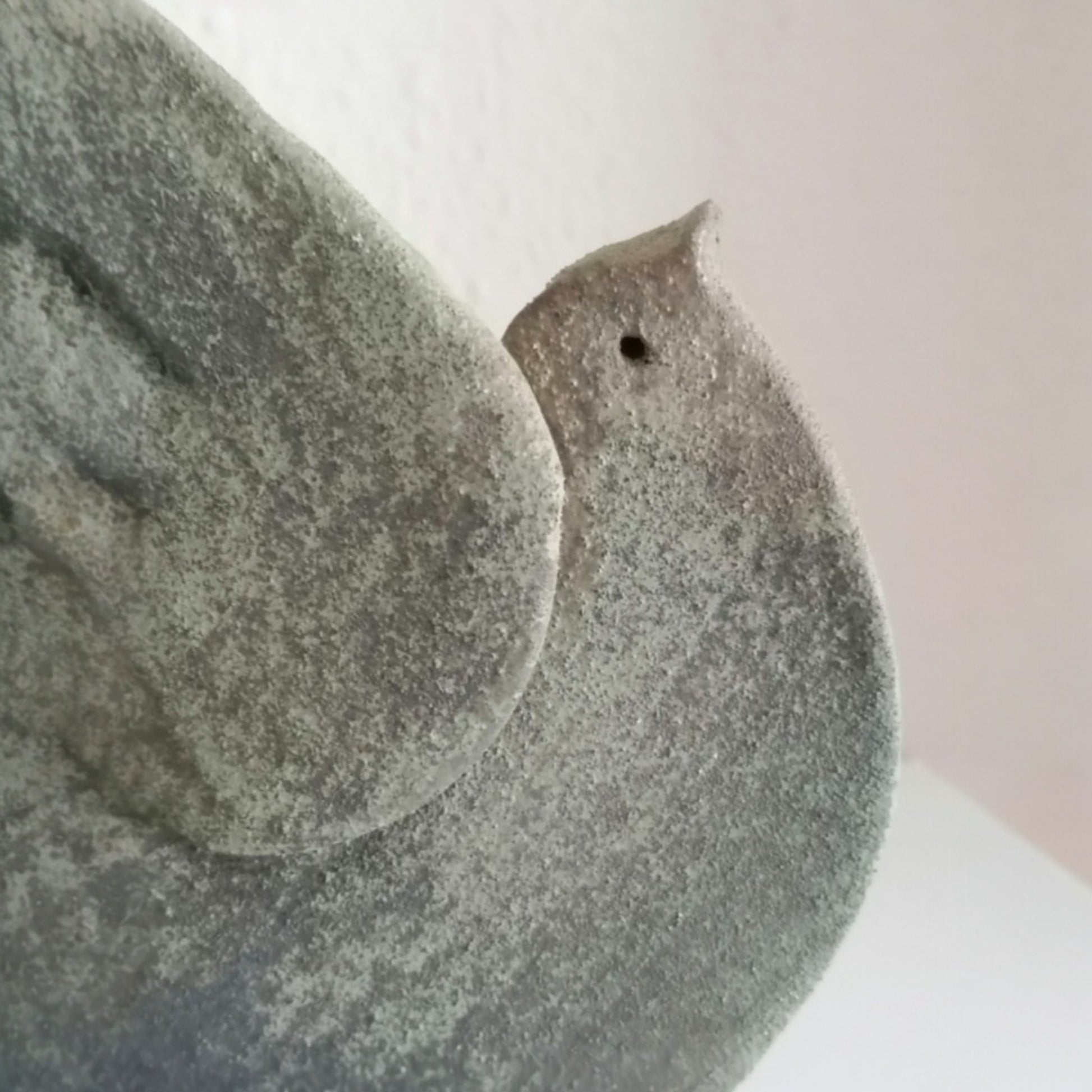 Close view of the stylised head and textured surface of the ceramic dove 