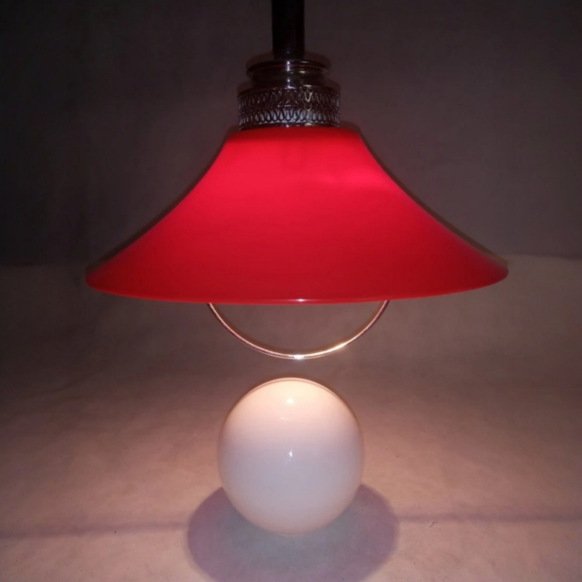 Red Space Age pendant lamp illuminated above the opaline glass globe