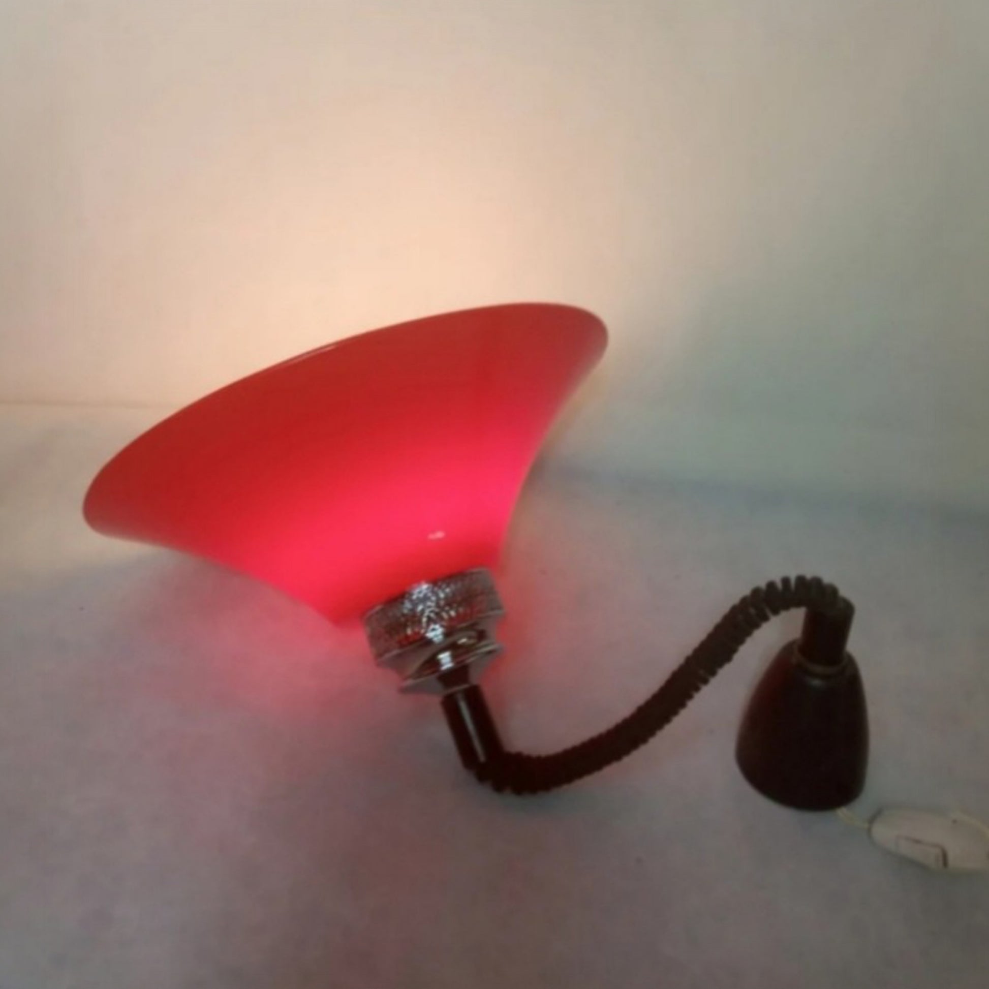 Illuminated side view showing the flexible suspension and red moulded plastic shade