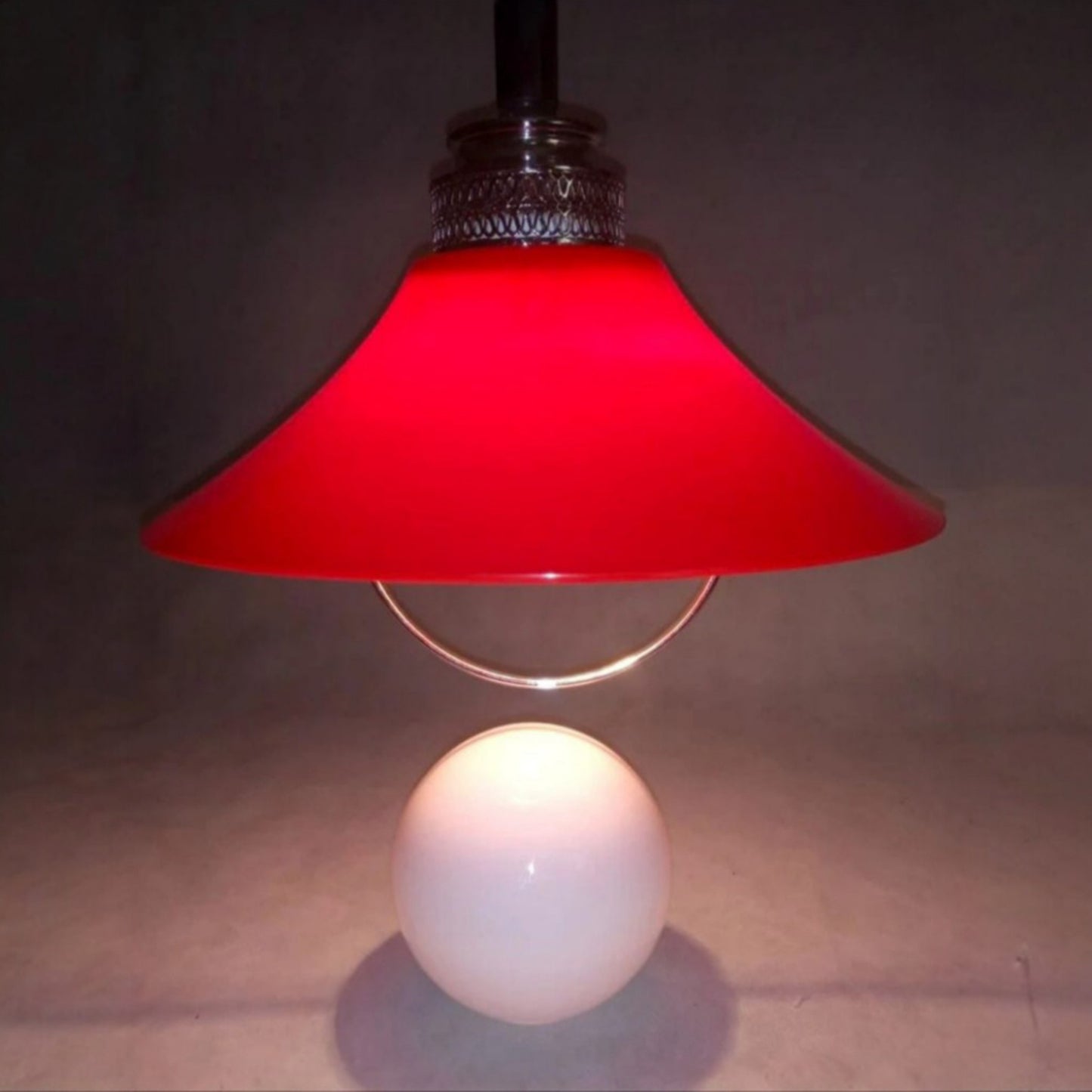 Red Space Age pendant lamp illuminated above the opaline glass globe