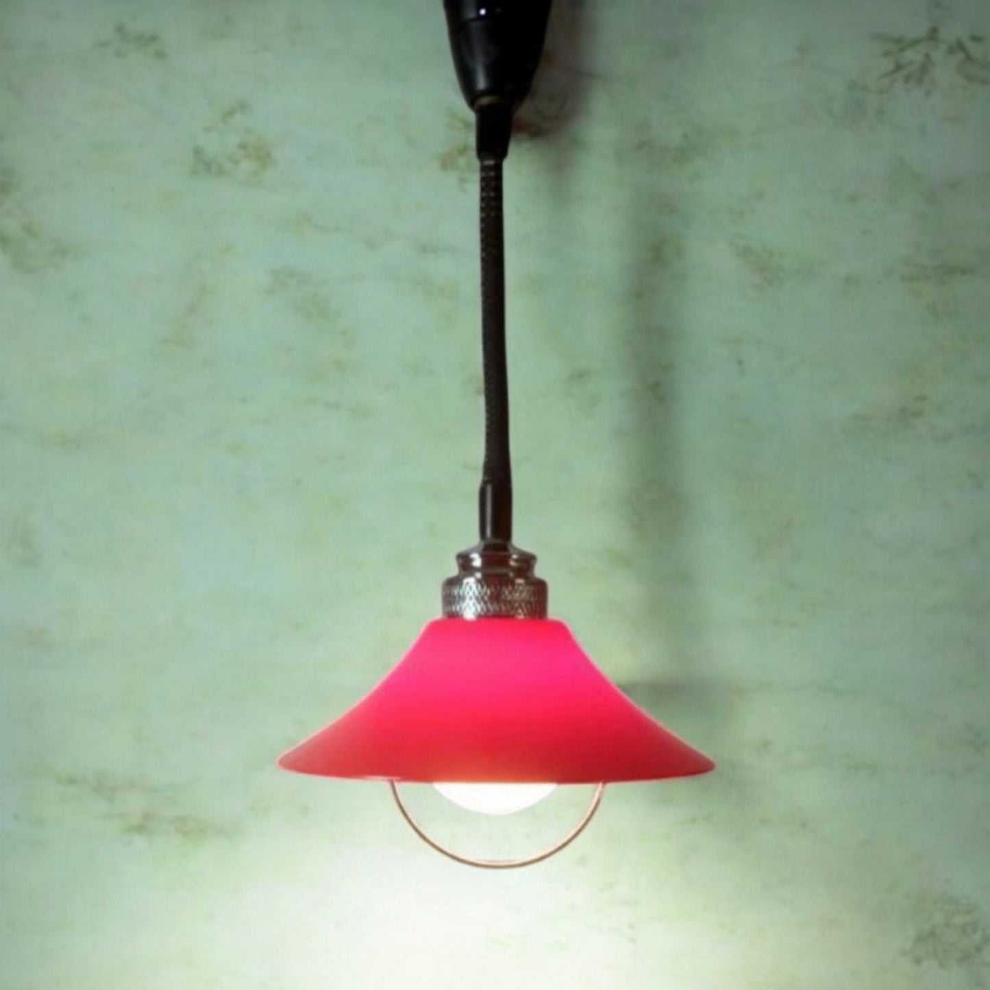 Red Space Age pendant lamp illuminated against a green background