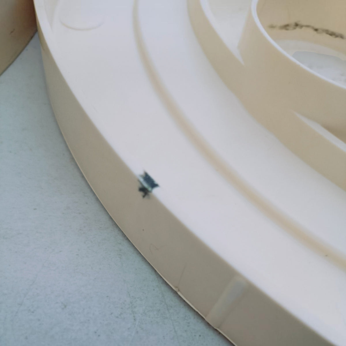 Detail of small dark mark, possibly from permanent marker  present on the base, facing towards the interior 