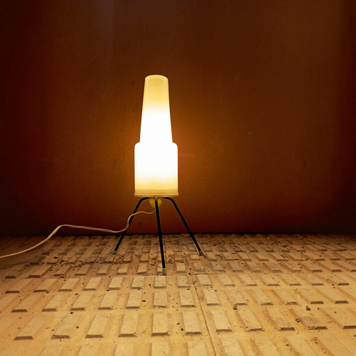 Opal plastic table lamp illuminated against a warm-toned wall