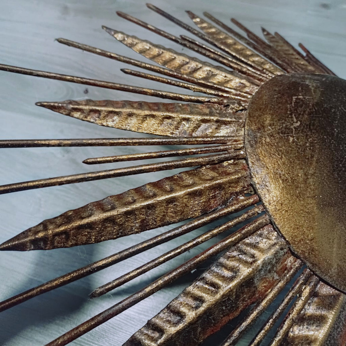 Angled close-up showing patina and surface wear across the gold-toned rays.